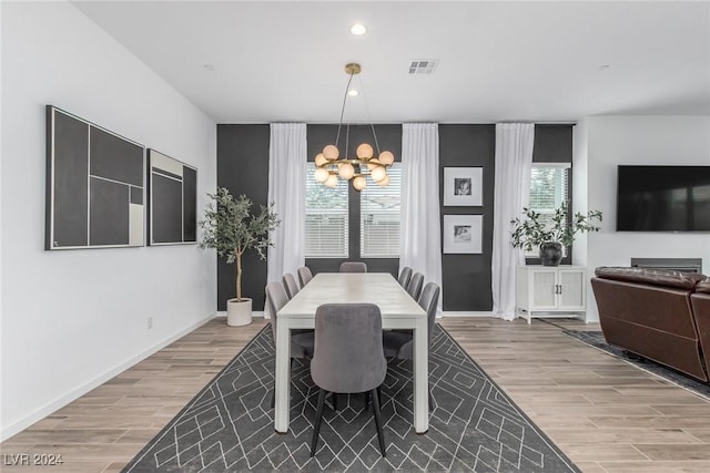 dining space with light hardwood / wood-style flooring and a chandelier