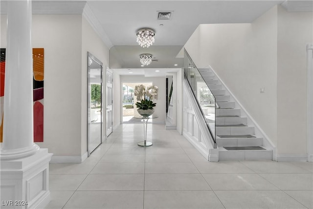 tiled foyer featuring decorative columns and a notable chandelier