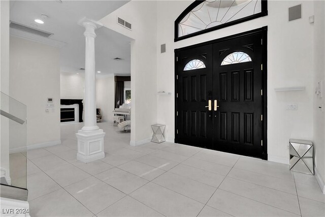 entryway featuring ornate columns, light tile patterned floors, and a high ceiling