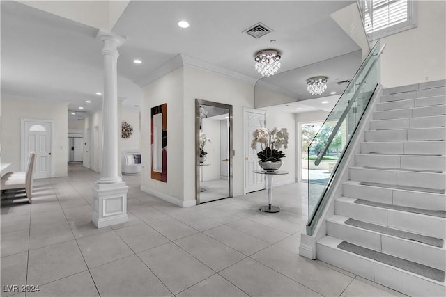 entrance foyer with ornate columns, crown molding, light tile patterned floors, and a notable chandelier