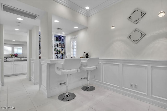 bar featuring pendant lighting, light tile patterned floors, white cabinetry, and ornamental molding