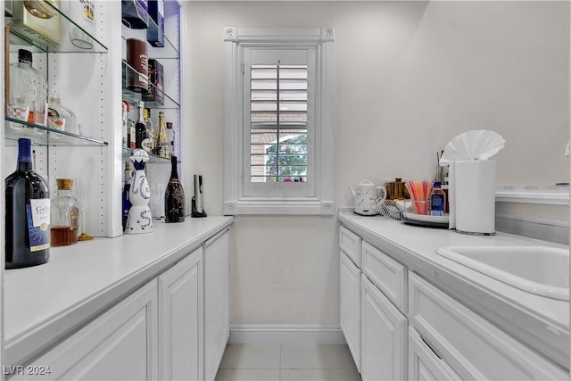 bar with white cabinetry, sink, and light tile patterned flooring