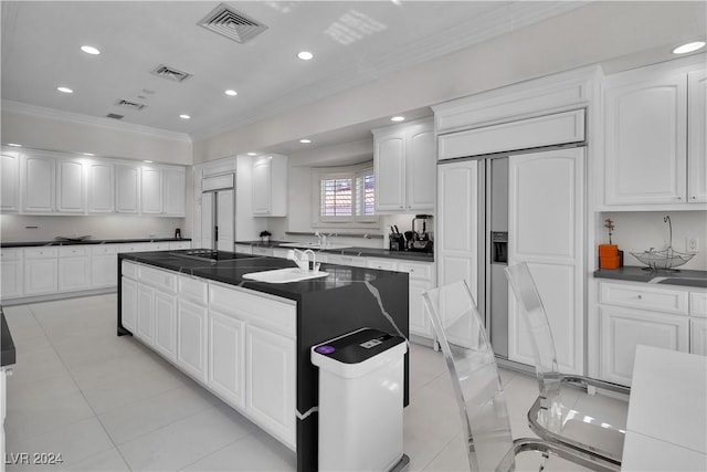 kitchen featuring paneled built in refrigerator, white cabinetry, ornamental molding, and light tile patterned flooring