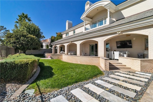 rear view of house featuring a lawn and a patio area