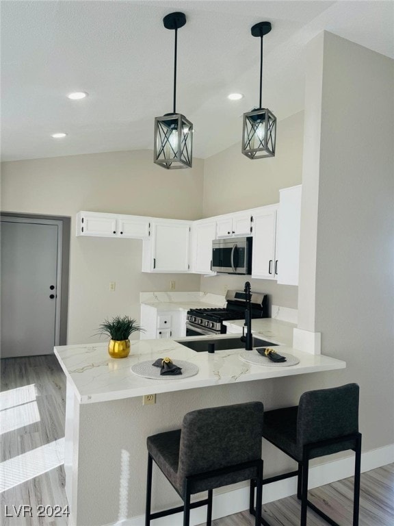 kitchen featuring light hardwood / wood-style flooring, hanging light fixtures, stainless steel appliances, kitchen peninsula, and white cabinets