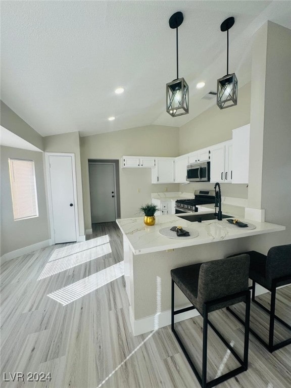 kitchen with lofted ceiling, kitchen peninsula, pendant lighting, white cabinetry, and appliances with stainless steel finishes