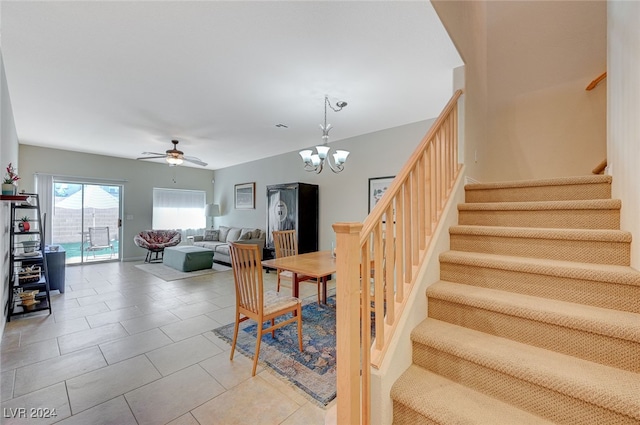 stairs with tile patterned floors and ceiling fan with notable chandelier