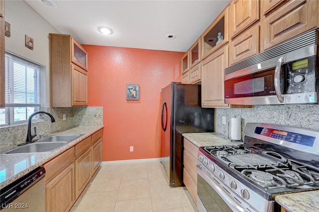 kitchen featuring sink, light stone counters, stainless steel appliances, and light tile patterned floors