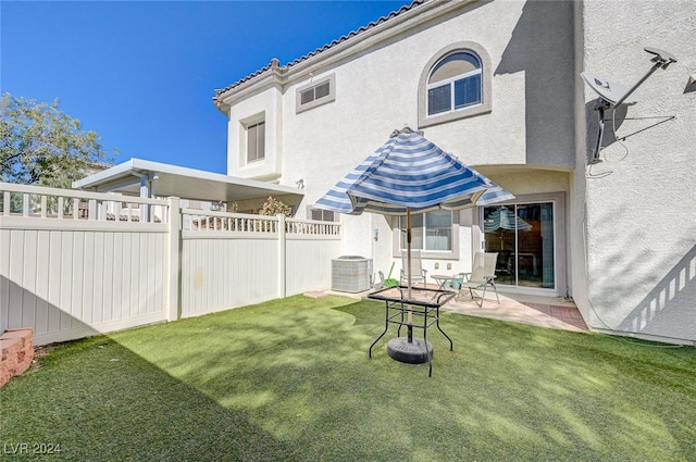 back of property with central air condition unit, a patio area, and a lawn