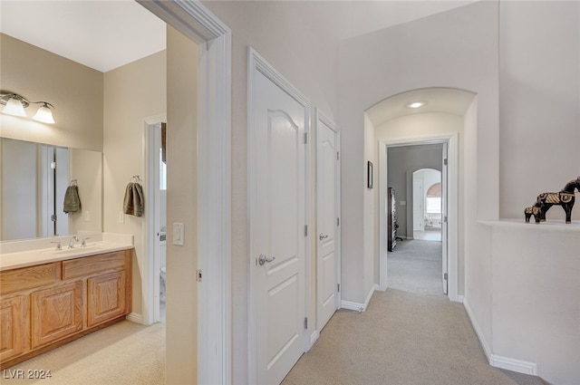 corridor with light colored carpet and sink