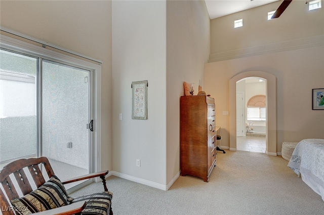 interior space featuring a high ceiling, light carpet, and ceiling fan