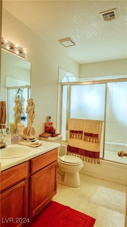 full bathroom featuring vanity, combined bath / shower with glass door, a textured ceiling, and toilet