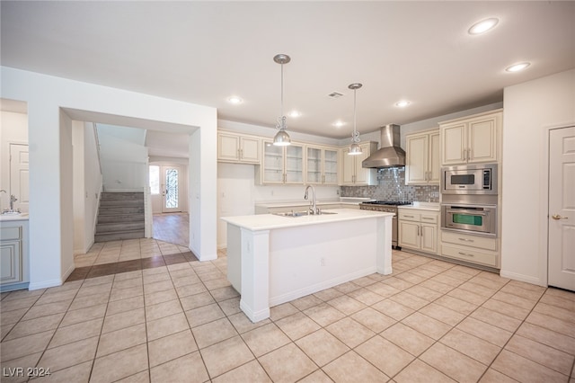 kitchen featuring stainless steel appliances, wall chimney exhaust hood, hanging light fixtures, and cream cabinetry