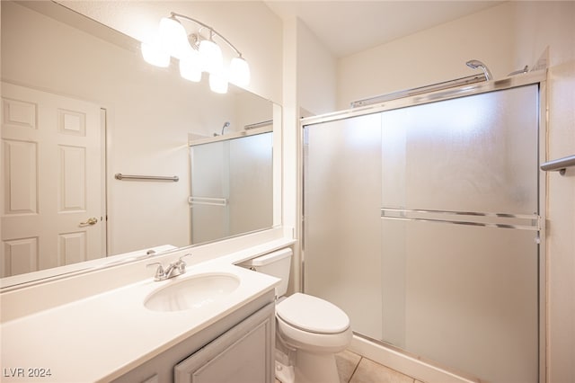 bathroom with tile patterned floors, vanity, an enclosed shower, and toilet