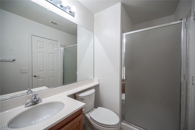 bathroom with vanity, toilet, and a shower with shower door