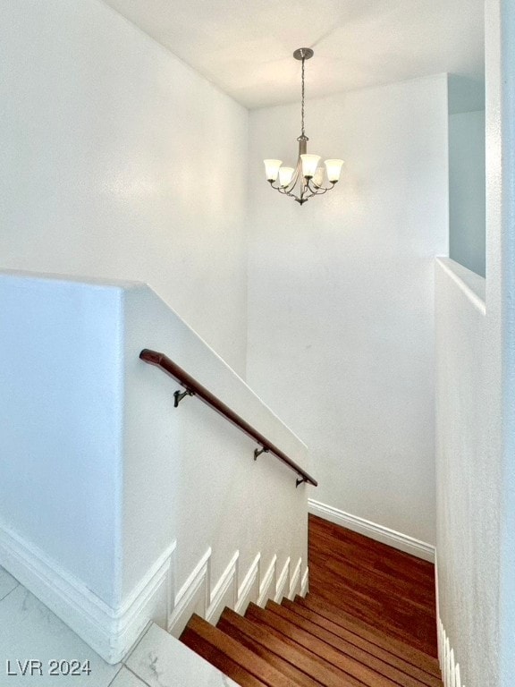 stairs featuring a notable chandelier and wood-type flooring