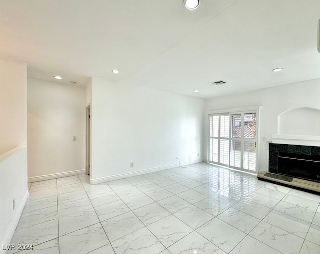 unfurnished room featuring a tile fireplace