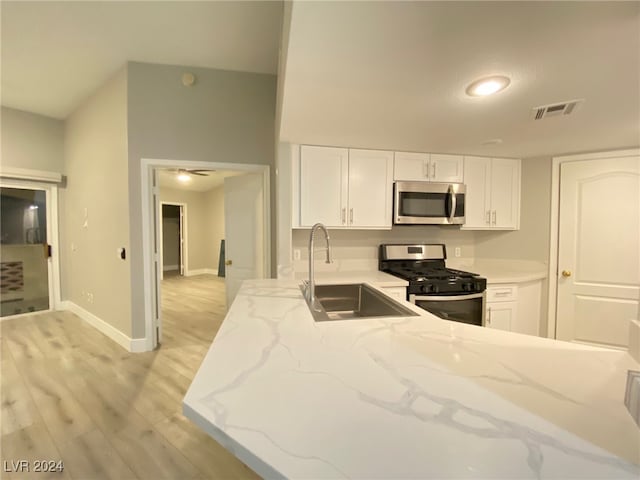 kitchen featuring light stone countertops, appliances with stainless steel finishes, sink, light hardwood / wood-style floors, and white cabinets