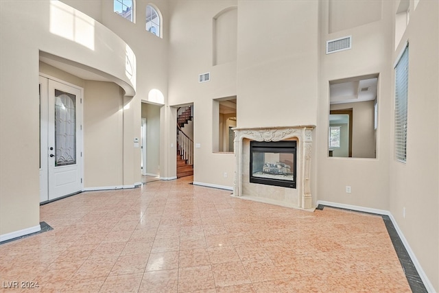 unfurnished living room featuring a wealth of natural light, a premium fireplace, and a high ceiling