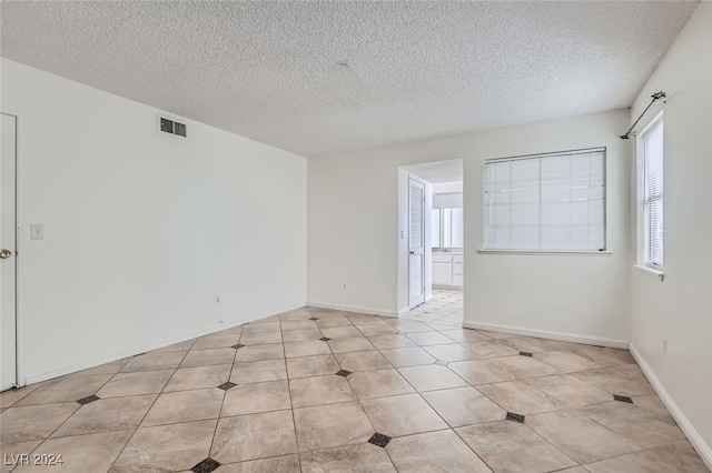 unfurnished room featuring a textured ceiling and light tile patterned floors