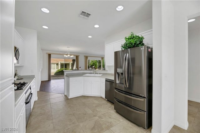 kitchen with sink, stainless steel appliances, an inviting chandelier, kitchen peninsula, and white cabinets