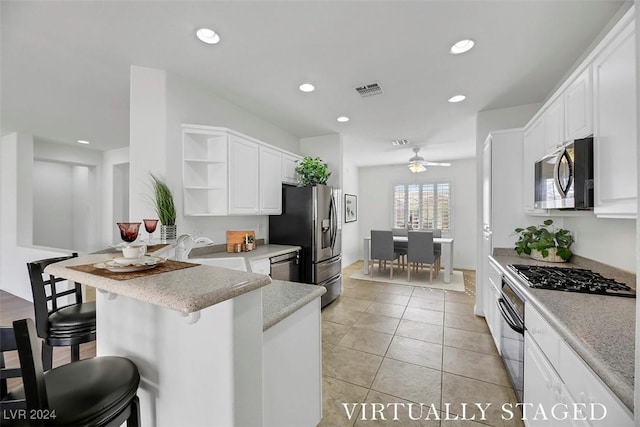 kitchen with kitchen peninsula, appliances with stainless steel finishes, white cabinets, and a kitchen breakfast bar