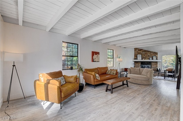 living room featuring beamed ceiling, light hardwood / wood-style flooring, and a fireplace