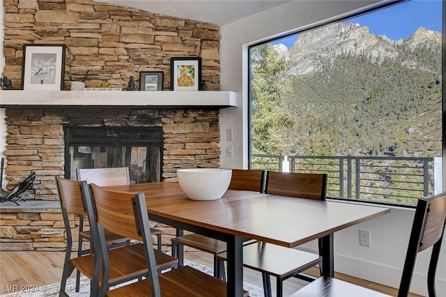 dining space with a stone fireplace and hardwood / wood-style flooring