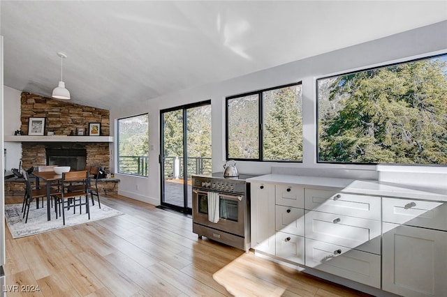 kitchen with lofted ceiling, light hardwood / wood-style flooring, high end range, decorative light fixtures, and white cabinets