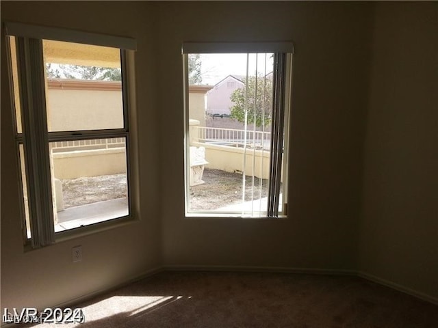 unfurnished room with a wealth of natural light and dark carpet