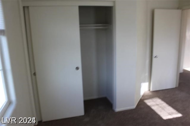 unfurnished bedroom with a closet and dark carpet