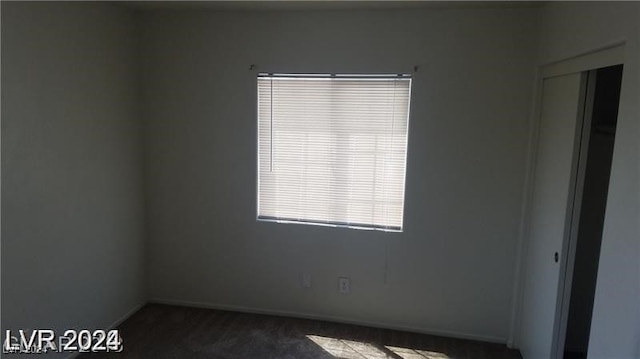 unfurnished room with dark colored carpet