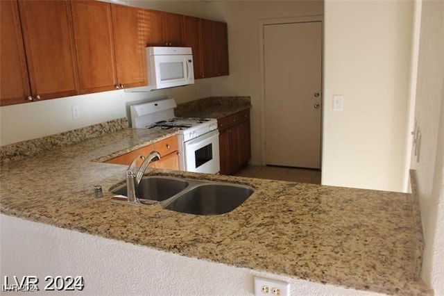 kitchen featuring sink, light stone counters, white appliances, and kitchen peninsula