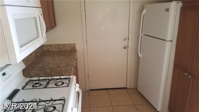 kitchen featuring white cabinets, light tile patterned flooring, and white appliances