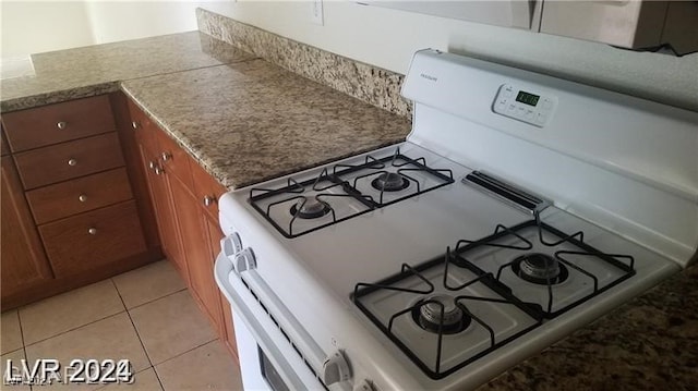 kitchen with light tile patterned flooring and white gas range oven