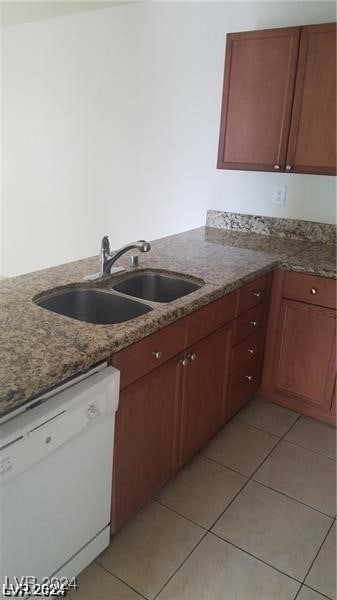 kitchen featuring sink, dishwasher, dark stone countertops, and light tile patterned floors