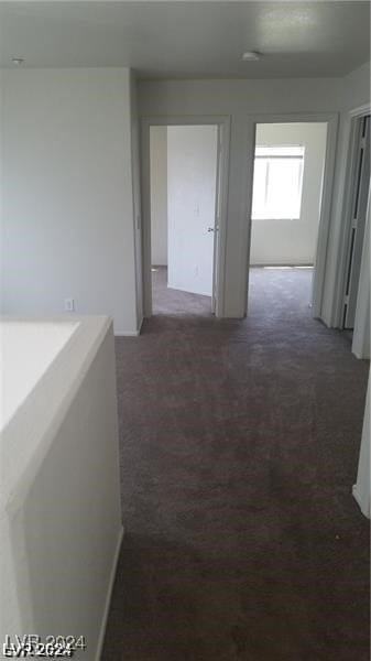 hallway featuring dark colored carpet