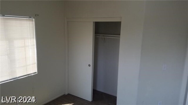 unfurnished bedroom featuring dark colored carpet and a closet