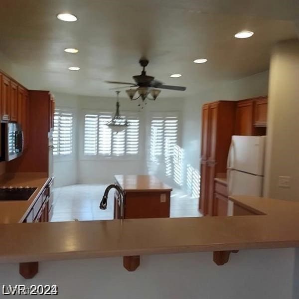 kitchen featuring sink, a kitchen breakfast bar, black cooktop, and white refrigerator