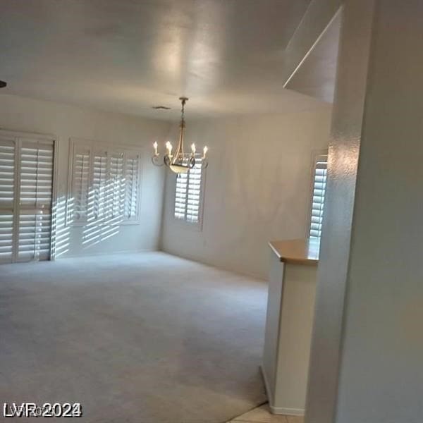 carpeted spare room with a chandelier