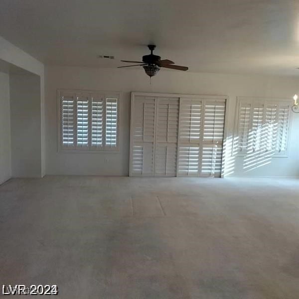 interior space featuring carpet floors and ceiling fan with notable chandelier