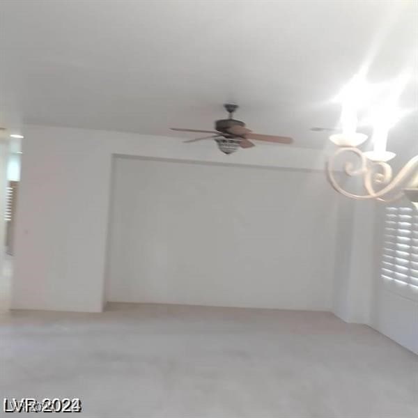 unfurnished room featuring ceiling fan with notable chandelier