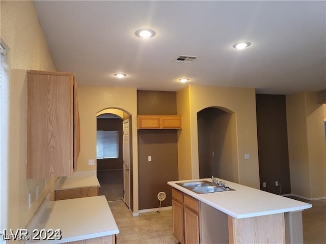 kitchen featuring light tile patterned floors, sink, light brown cabinets, and a kitchen island with sink