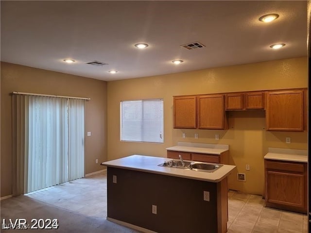 kitchen featuring light tile patterned flooring, sink, and an island with sink