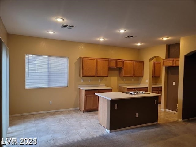 kitchen with black electric stovetop and a center island with sink