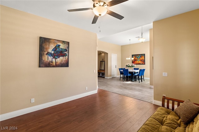 living room featuring ceiling fan with notable chandelier and hardwood / wood-style flooring