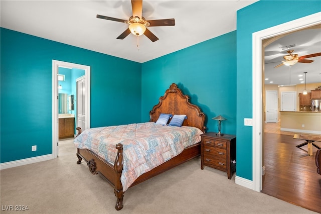 bedroom featuring light wood-type flooring, ensuite bath, ceiling fan, and stainless steel fridge with ice dispenser