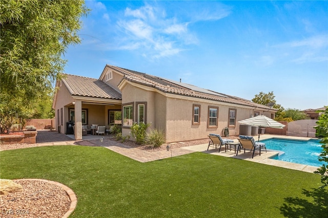 rear view of property with a yard, a fenced in pool, and a patio