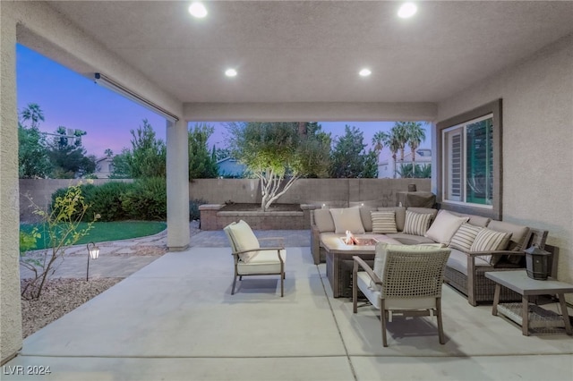 patio terrace at dusk with an outdoor living space with a fire pit