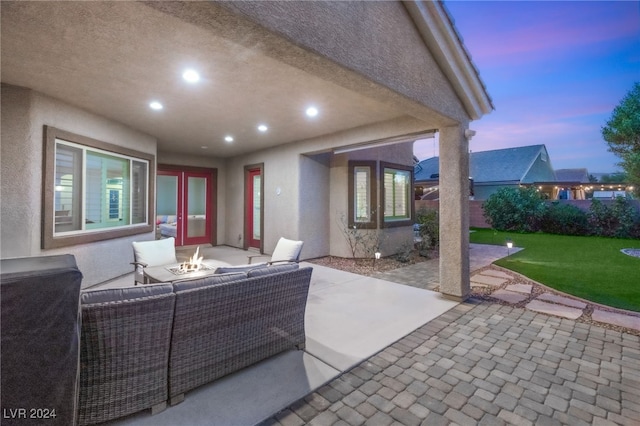 patio terrace at dusk with a lawn and an outdoor living space with a fire pit